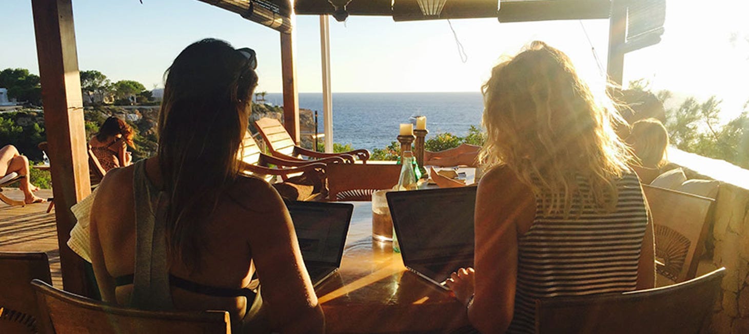 Rip Curl crew working on their laptops, in a bar by the beach at sunset