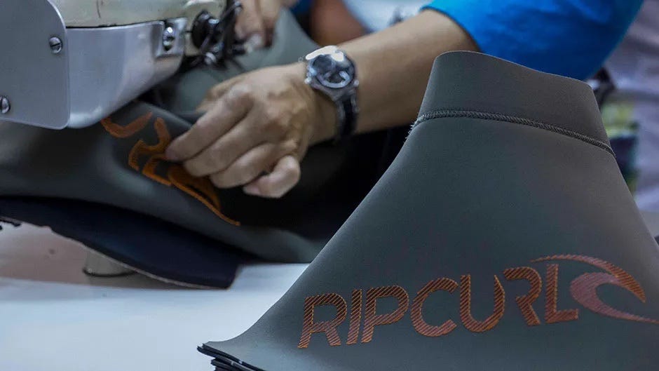 close up shot of crew stitching a Rip Curl wetsuit with a sewing machine