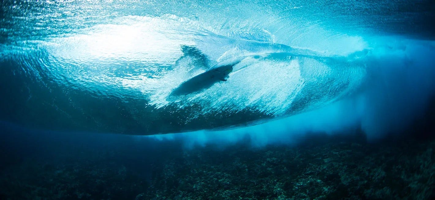 A surfer in the barrel of a wave, viewed from underwater