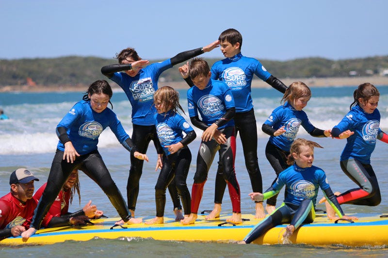 Groms training their balance on a giant surfboard